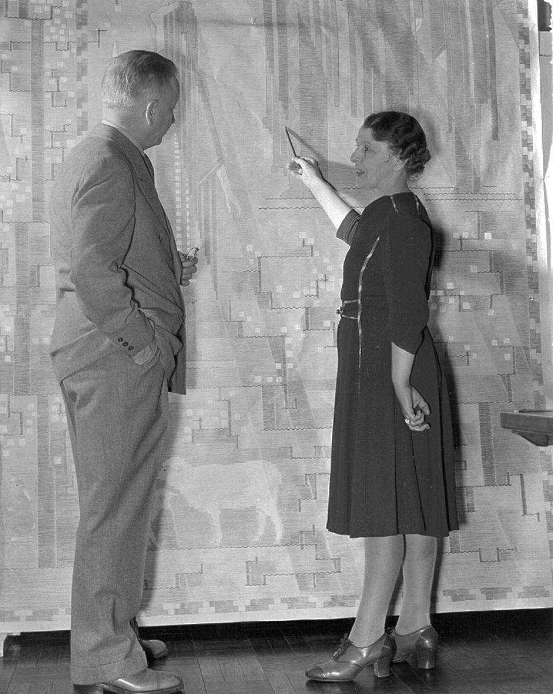 Loja Saarinen showing Eliel Saarinen a cartoon of their tapestry, The Sermon on the Mount, April 1941. Betty Truxell, photographer. Courtesy of Cranbrook Archives.  