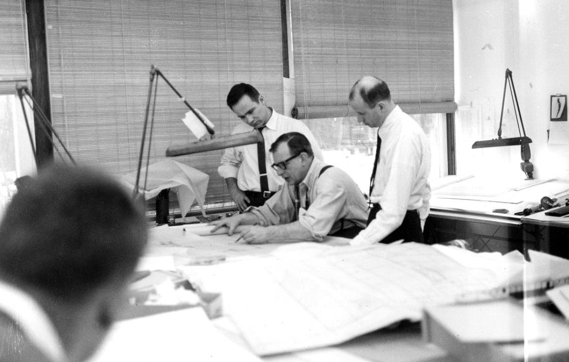 Photograph of Eero Saarinen and two associates at a drafting table. 