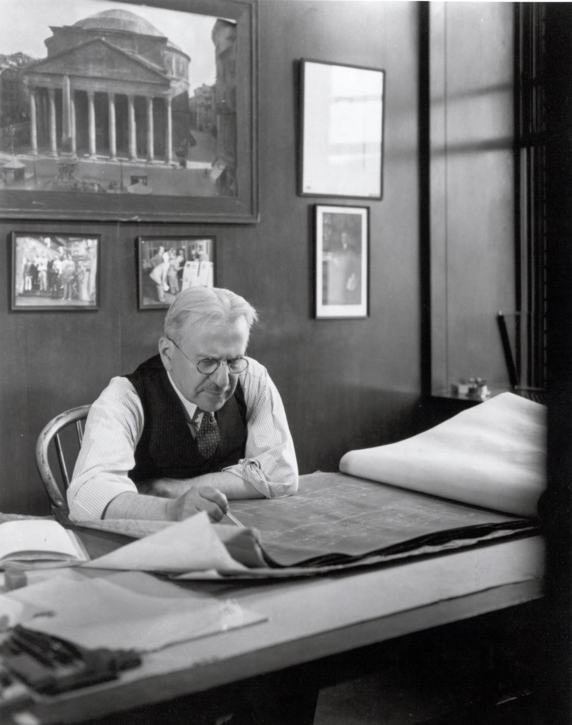 Photograph of Albert Kahn at his desk with an image of the Pantheon behind him