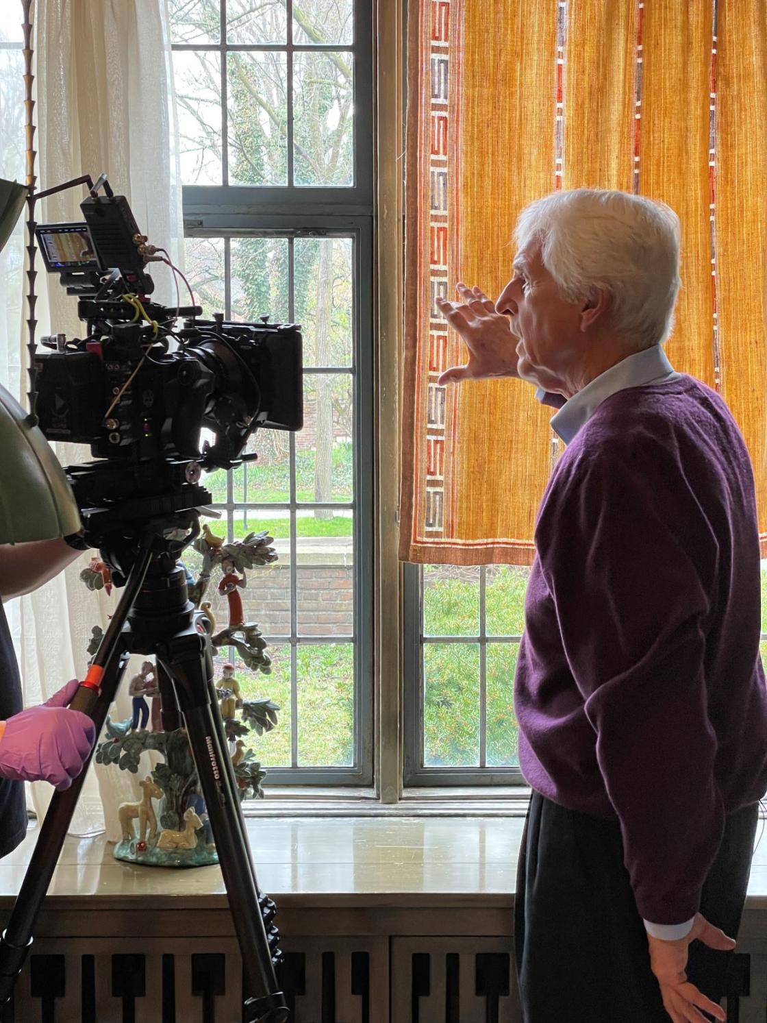 Photograph of Gerhardt Knodel pointing out a detail of a Studio Loja Saarinen curtain on camera