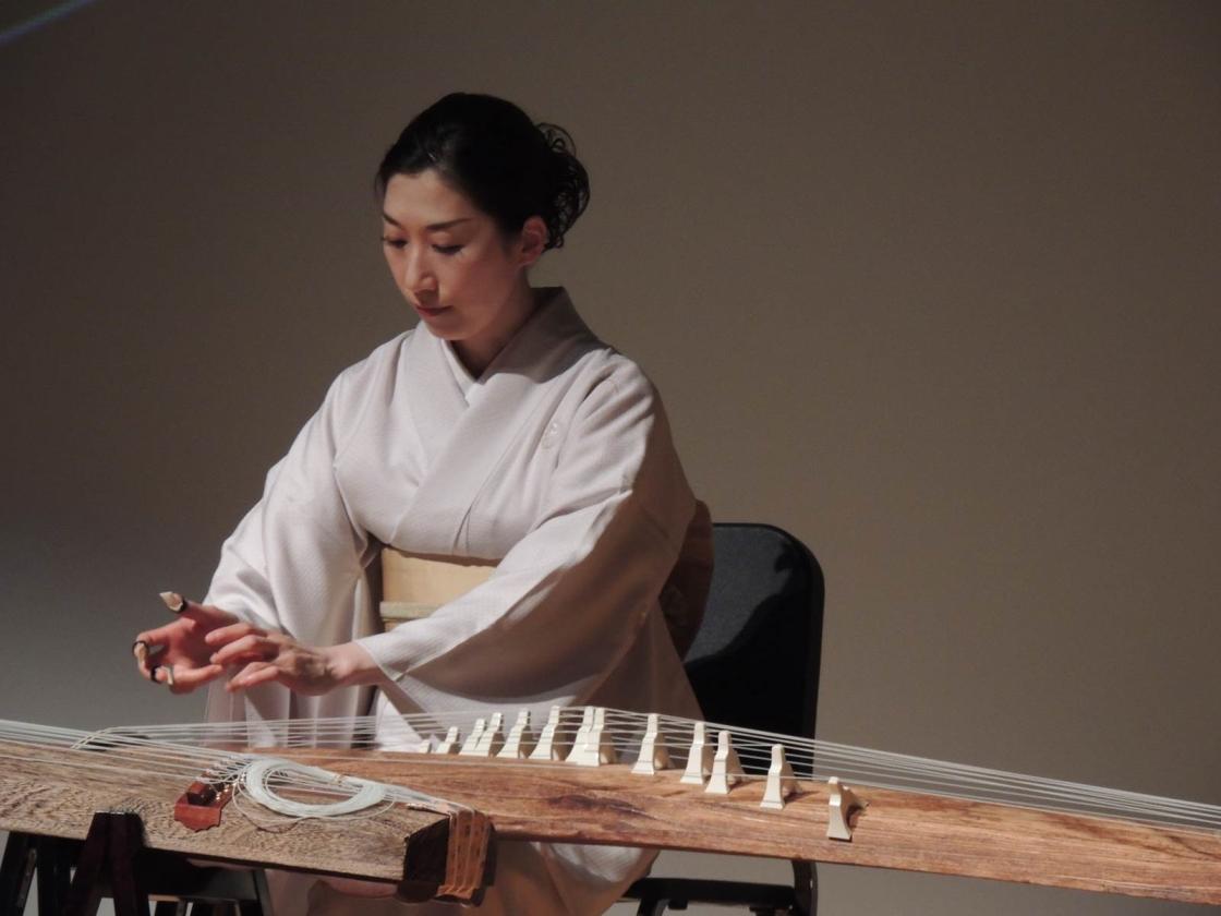 Yuko Asano playing a traditional Japanese stringed instrument, the koto