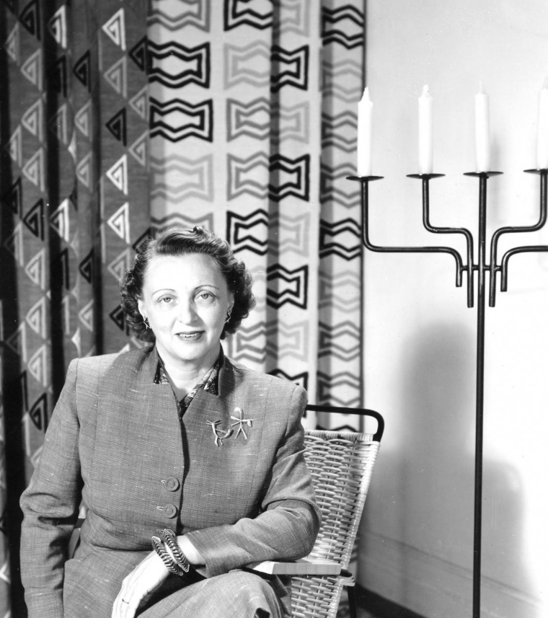 Photograph of Pipsan Saarinen Swanson in front of drapes and a candelabra she designed.